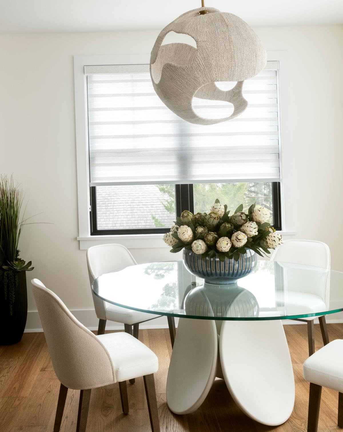 Dining nook with woven pendant, glass table, and protea centerpiece
