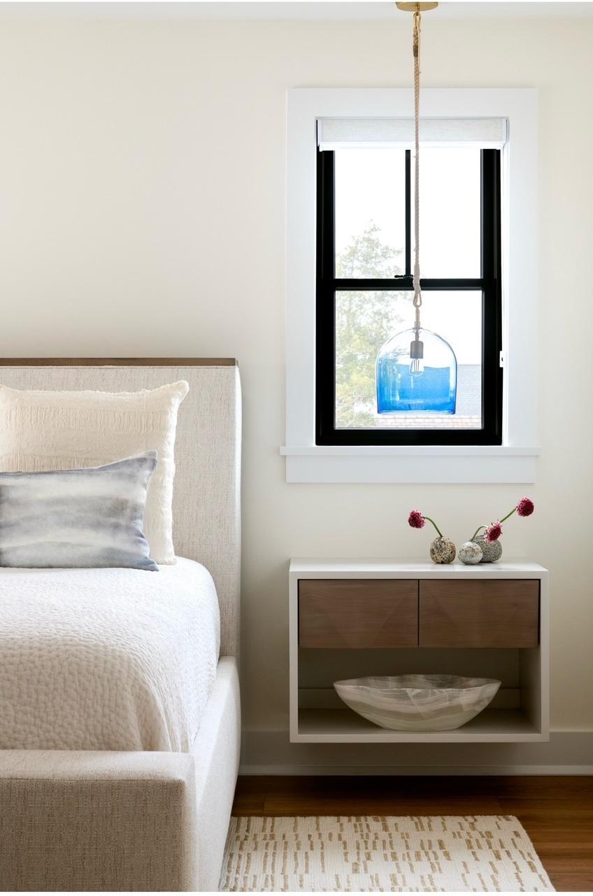 Bedroom with floating nightstand, bud vases, and blue glass pendant