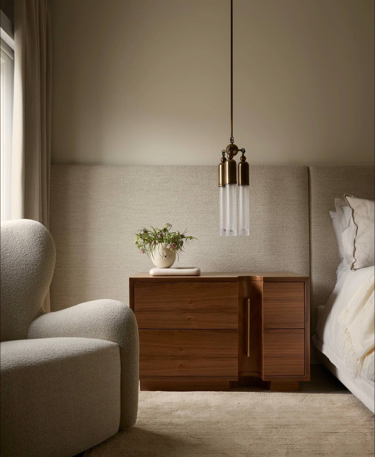 Bedroom corner with walnut nightstand and glass pendant
