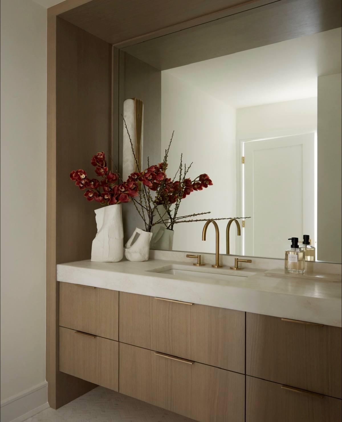 Powder room vanity with red branches in white sculptural vases