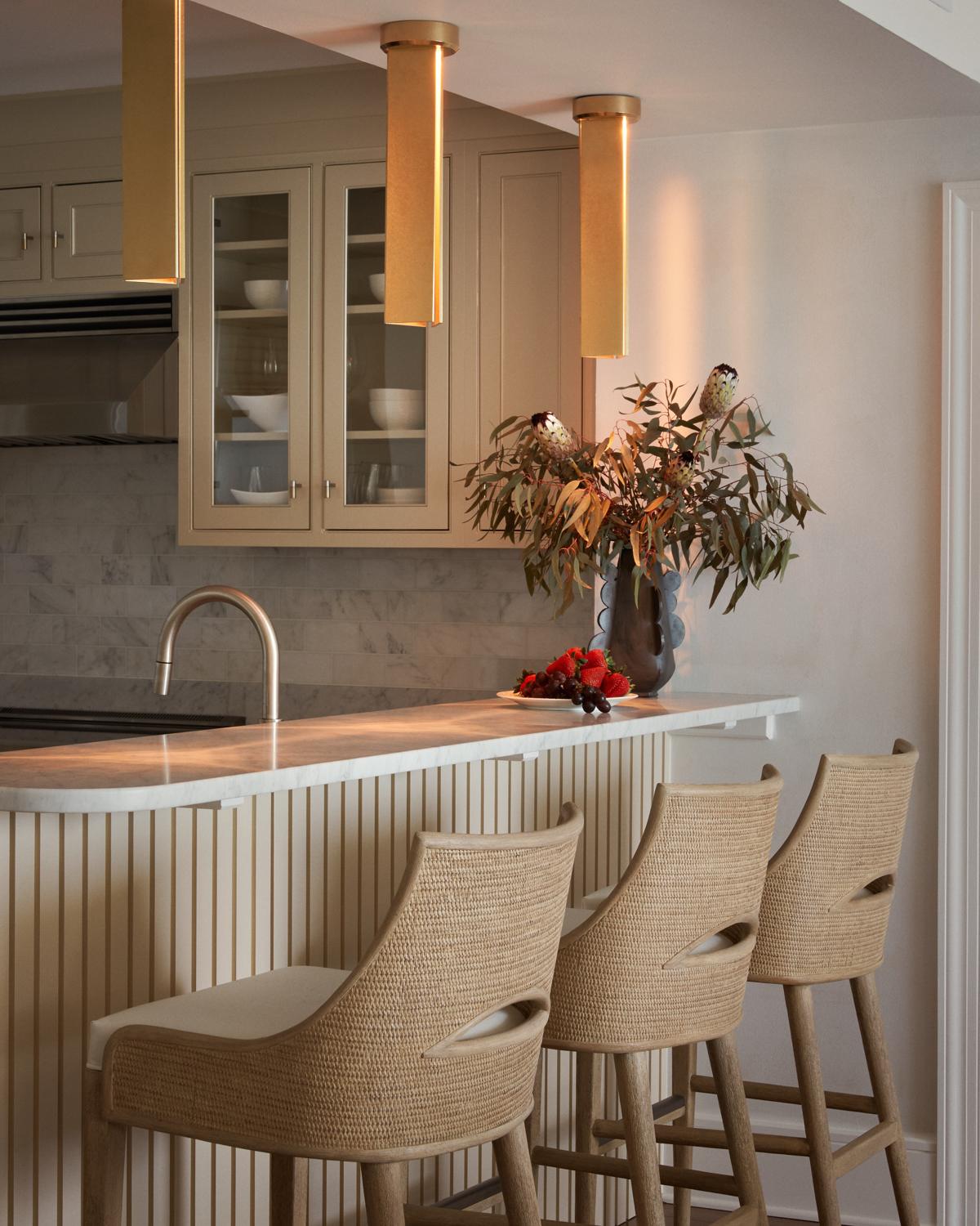 Kitchen bar with brass cylinder pendants and woven counter stools