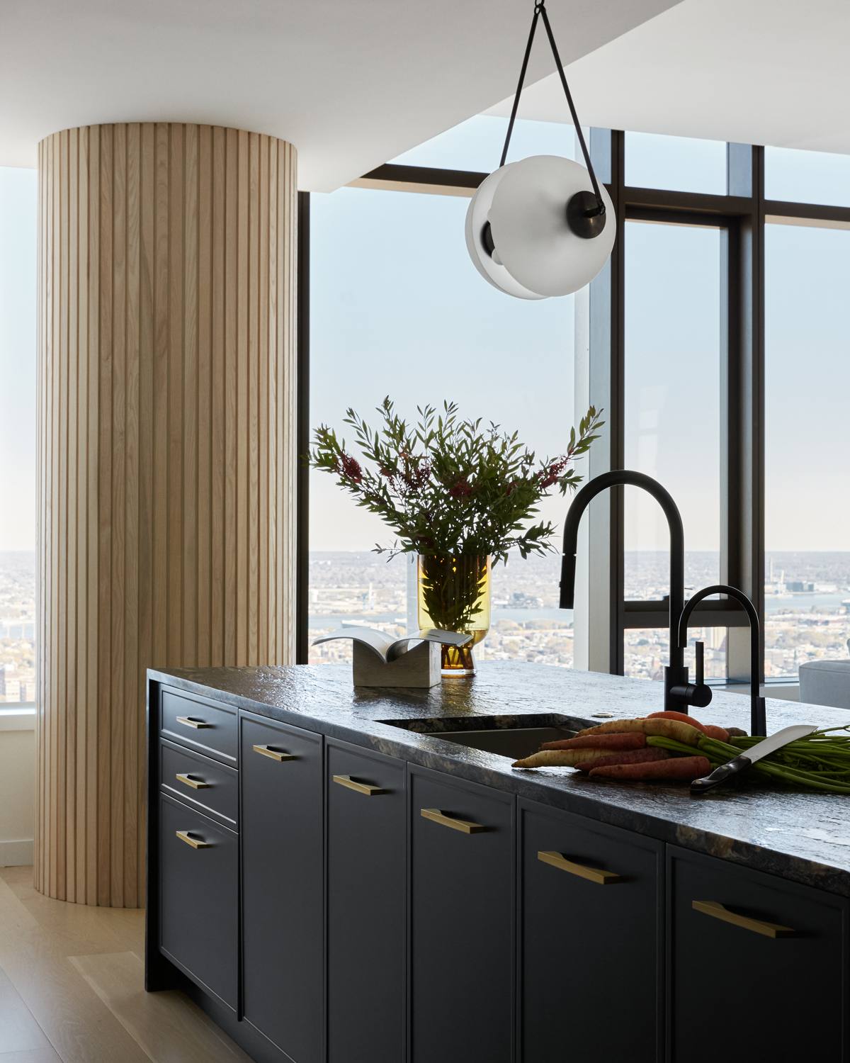 Kitchen at The Laurel with black stone island, fluted wood column, and Philadelphia skyline views
